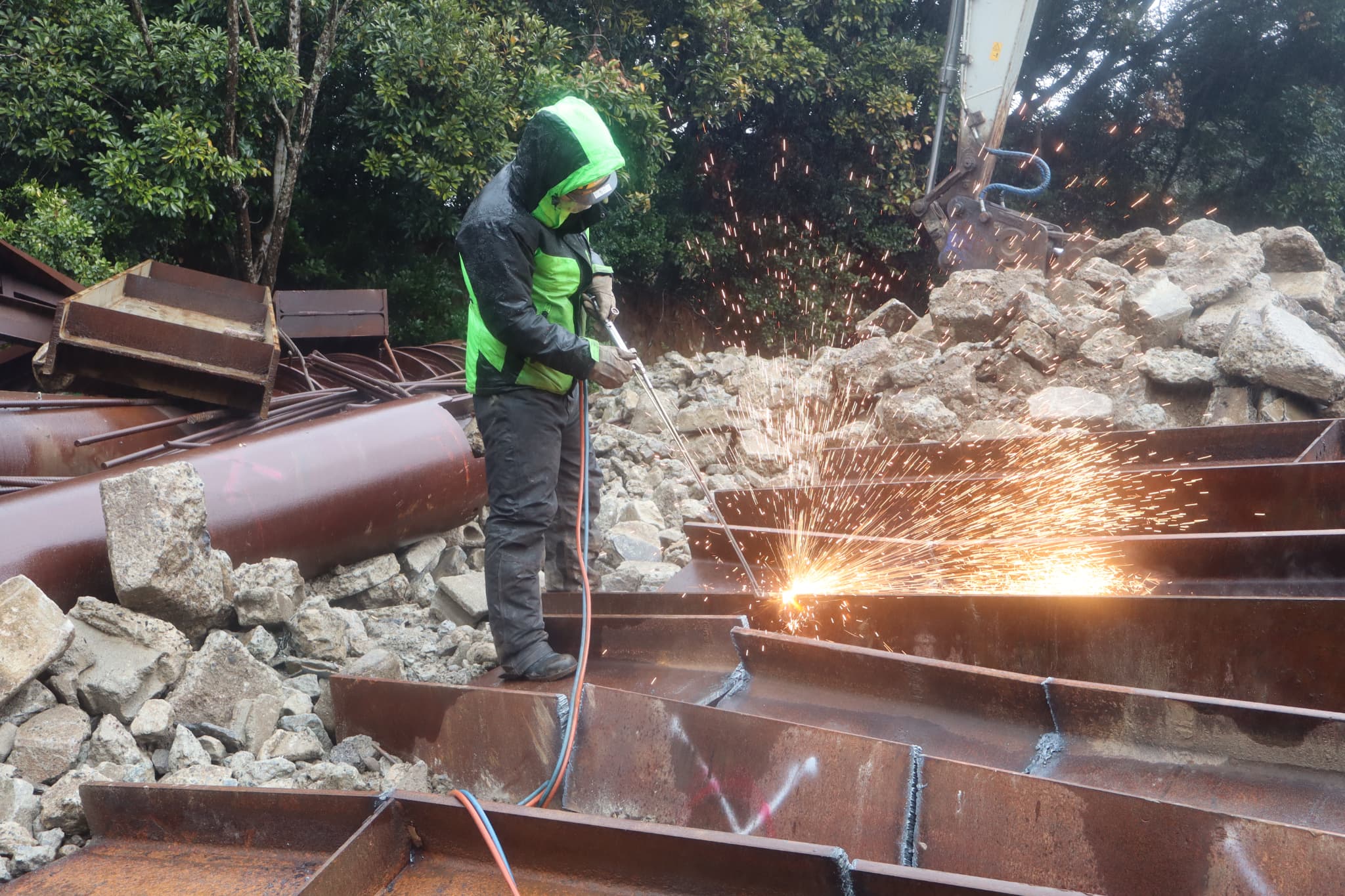 UCHIKAWAの溶断加工作業。作業員がガストーチで鉄骨H形鋼を切断し、火花が飛び散る様子